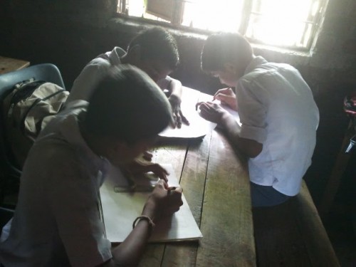 Children at the school stop to think for a minute, and then pick up their pencils and start drawing their vision of an ideal school.