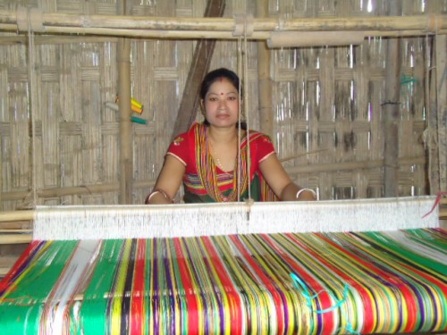 A Hajong woman weaving a beatiful multi-hued garment.