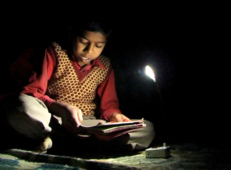 Boy studying with solar LED light provided by OCOL