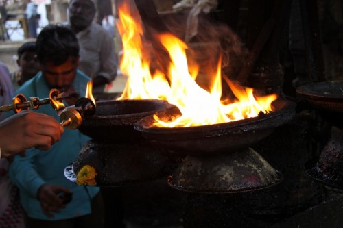 Lighting the temple lamps with a 'divti', a smaller lamp in the shape of a dagger.