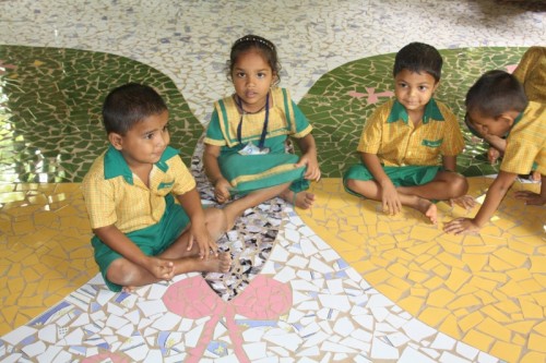 Happy children playing on the butterfly mosaic on the school floor
