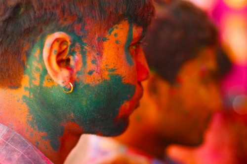 A boy shopping in the main market of the town with gulaal stains on the cheeks.