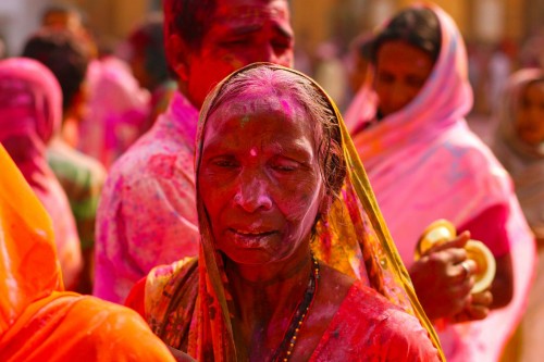 An elderly Indian lady playing Holi in the Sri Sri Radha Govinda temple.