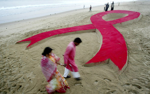 An Indian couple walk past a 50 foot (15.24 meter) long AIDS red ribbon sand sculpture, created by Sudarshan Pattnaik on World AIDS Day in Puri, India, Monday, Dec.1, 2008. (AP Photo/Biswaranjan Rout)