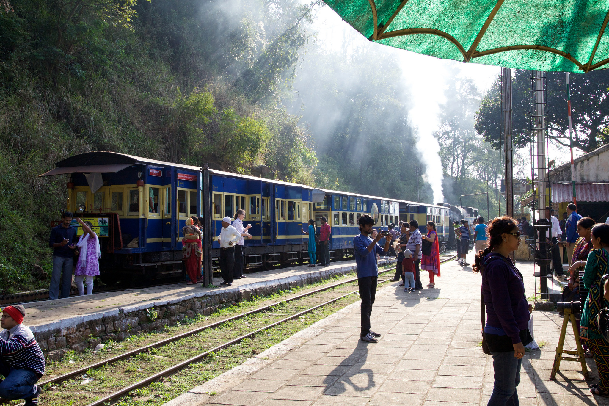 The Nilgiri Mountain Railway, cutting across the lush green hill side, with the engine at the back, pushing the train up the hills
