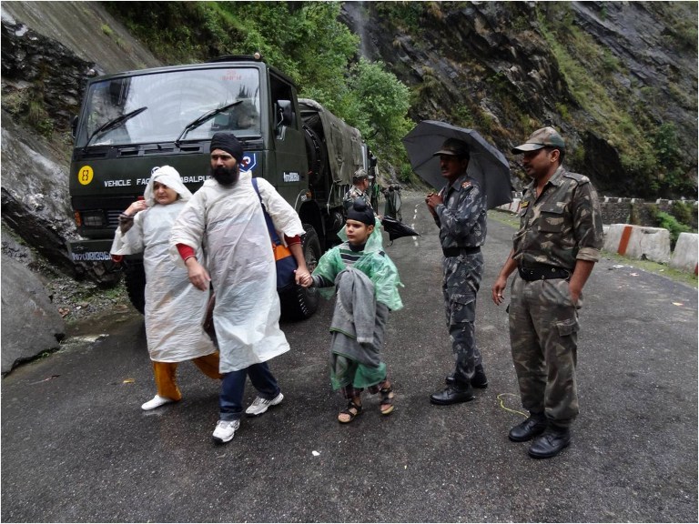 In this handout photograph released by The Indian Army on June 18, 2013, Indian Army officials escort stranded travellers along a road in Chamoli district in the northern Indian state of Uttarakhand on June 18, 2013. Torrential rains and flash floods washed away homes and roads in north India, leaving at least feared 60 people dead and thousands stranded, as the annual monsoon hit the country earlier than normal, officials said. Authorities called in military helicopters to try to rescue residents and pilgrims cut off by rising rivers and landslides triggered by more than three days of rain in the Himalayan state of Uttarakhand, officials said. -----EDITORS NOTE---- RESTRICTED TO EDITORIAL USE - MANDATORY CREDIT "AFP PHOTO / INDIAN ARMY" - NO MARKETING NO ADVERTISING CAMPAIGNS - DISTRIBUTED AS A SERVICE TO CLIENTS