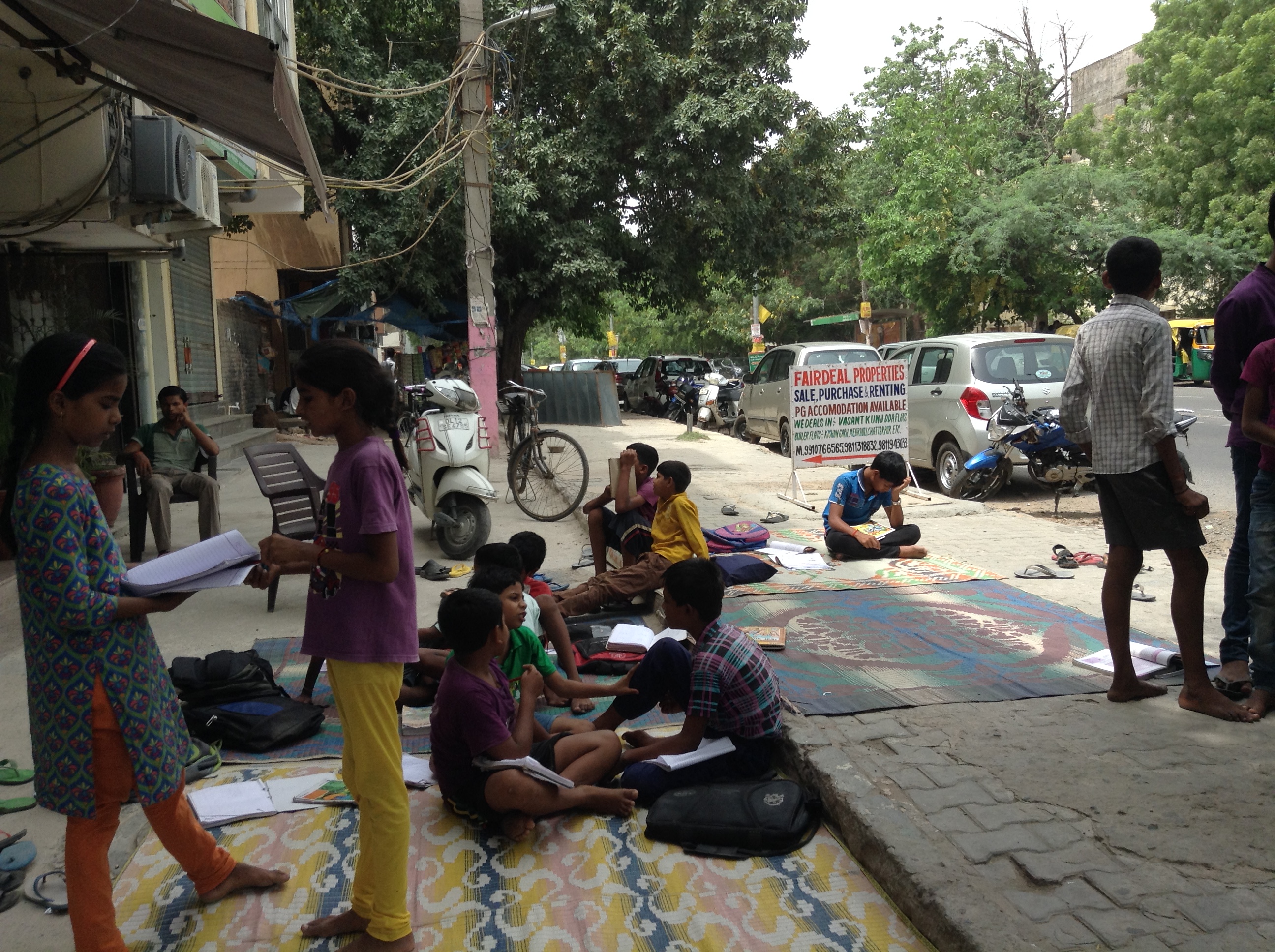 Children reading and learning on the pavement class-space 