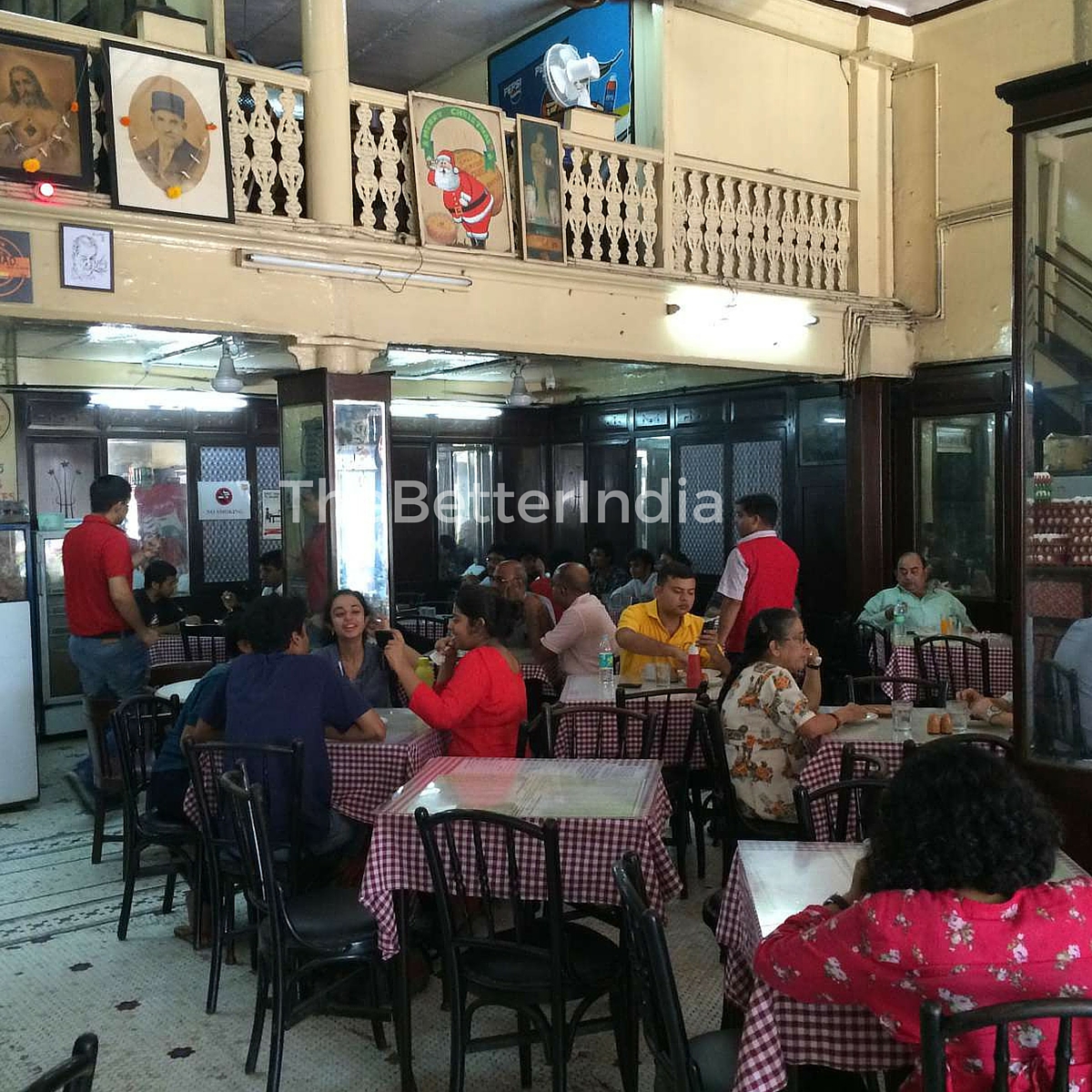 A bustling Kyani Bakery with its dark, aged wooden tables, covered with the quintessential red-and-white checked tablecloth. 