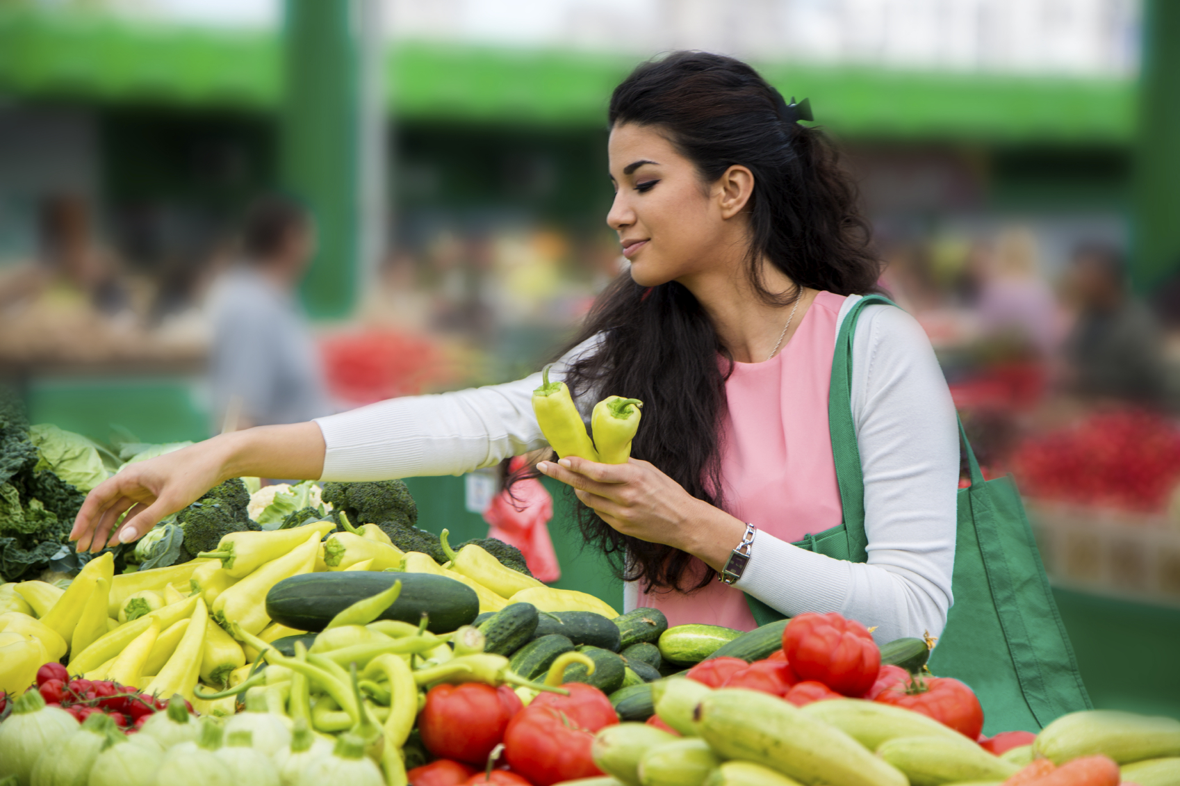 Pretty young woman buying vegetables on the market