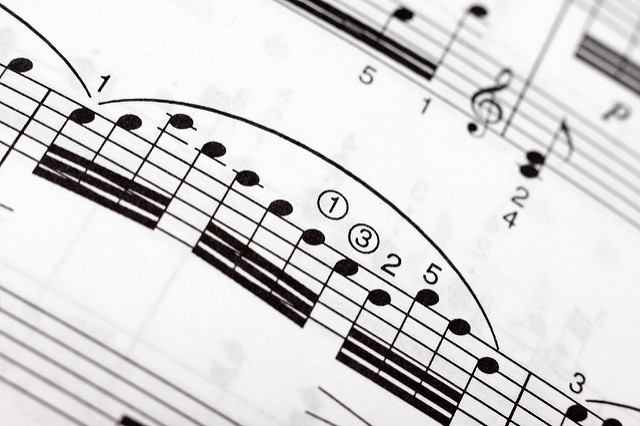 Groups of fast musical notes with a large legato arch over them on a music sheet, as part of a classical piece