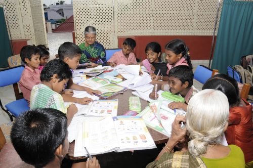 One of the senior residents of Anandam Old Age Home teach the children.