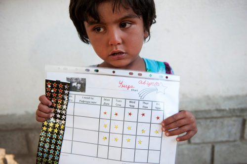 A 5-year-old living with MDR-TB holds up her star chart. She gets a sticker every time she takes her medicine properly. Incentives like these are used to help children take the drugs they need during their treatment. Photo: Wendy Marijnissen