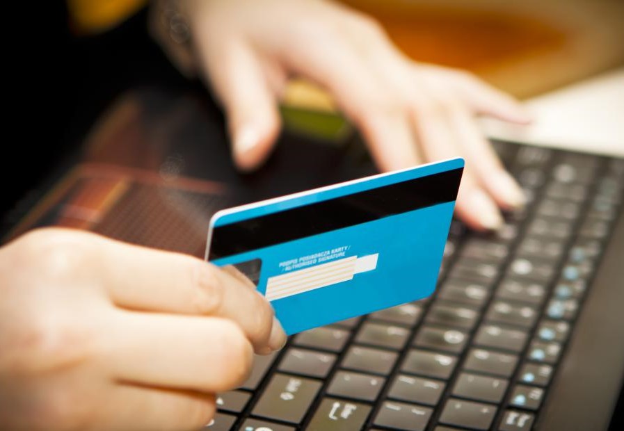 hand-holding-a-credit-card-at-a-computer-keyboard