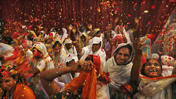 In this picture taken Sunday, March 24, 2013, Indian widows throw flowers during Holi celebrations, or the festival of colors, at an event organized by the NGO Sulabh at the Meera Sahbhagini Ashram in Vrindavan, India. The widows, many of whom at times have lived desperate lives in the streets of the temple town, celebrated Holi for the first time at the century old ashram. The women were banished by their families after their husband's deaths to the town where devotees believe Lord Krishna was born, for supposedly bringing bad luck. (AP Photo/Kevin Frayer)