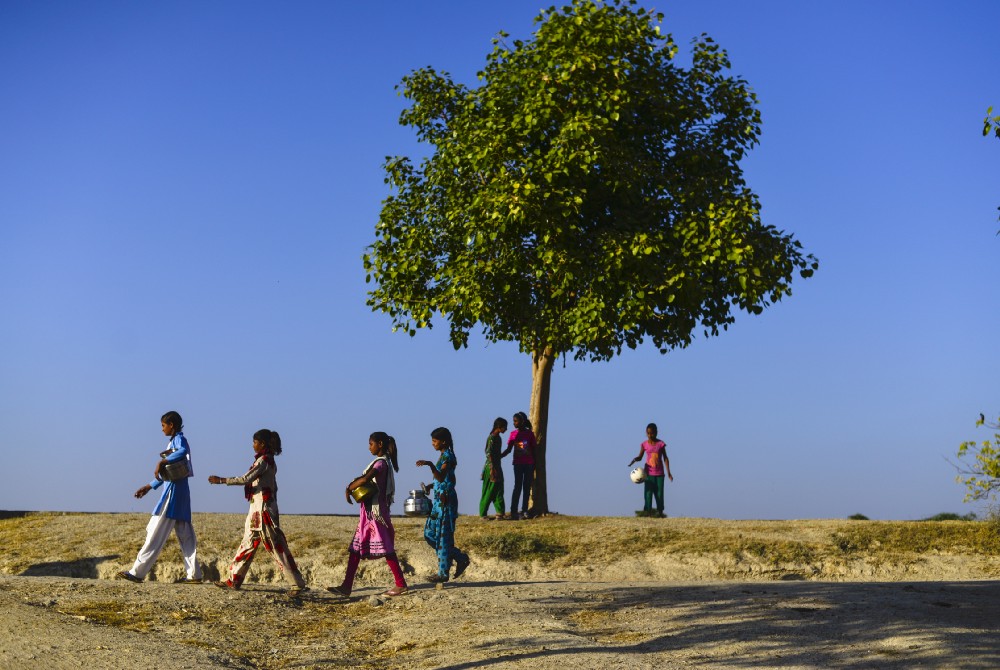 Girls walk past to fetch water from a nearby well, in Sakariya.
