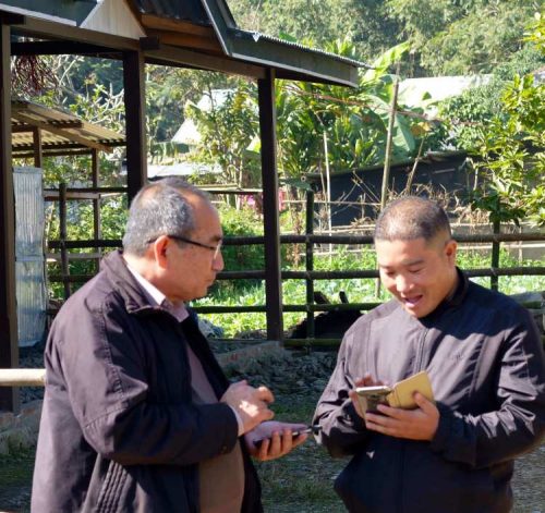 Tiken double-checking contact details while showing off recent photos on his camera to an employee