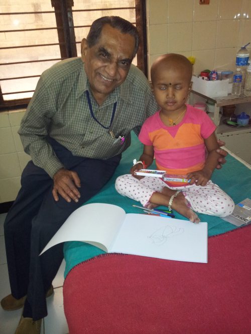 Ramaswamy happily helps child in some drawing activity in a hospital ward