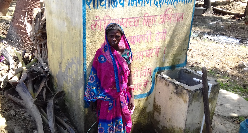 A village woman is standing in front of a newly constructed toilet at her home. (Photo by Mohd Imran Khan)