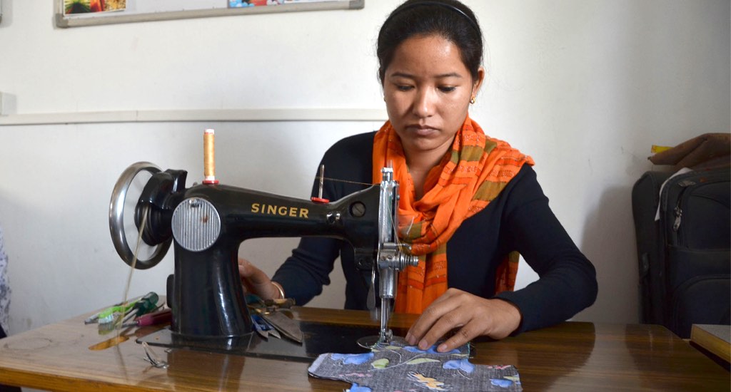 A young girl in Pamohi village stitches reusable sanitary pads for distribution among rural women. (Photo by Abdul Gani)