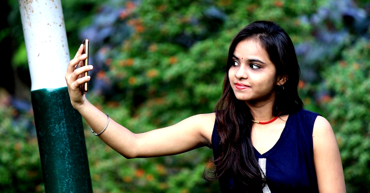 Indian couple posed outdoor, sitting on bench together and looking at  mobile phone, making selfie Stock Photo - Alamy