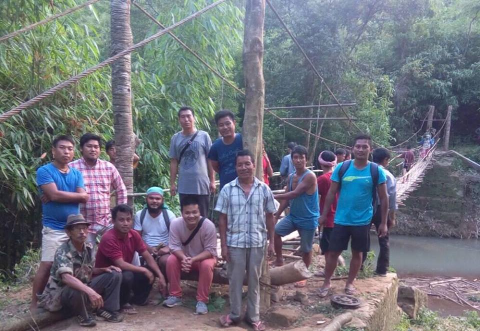 Aching Zeme standing in a shirt and grey pant with other villagers who worked on the hanging bridge. (Source: Facebook/Aching Zeme)