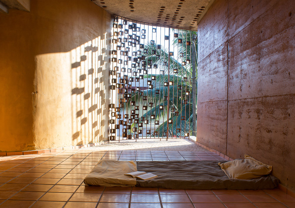 At the Biju Matthew residence site: The windows protected with meter boxes from a local scrapyard create a mural on the rammed earth walls. (Source: Wallmakers)