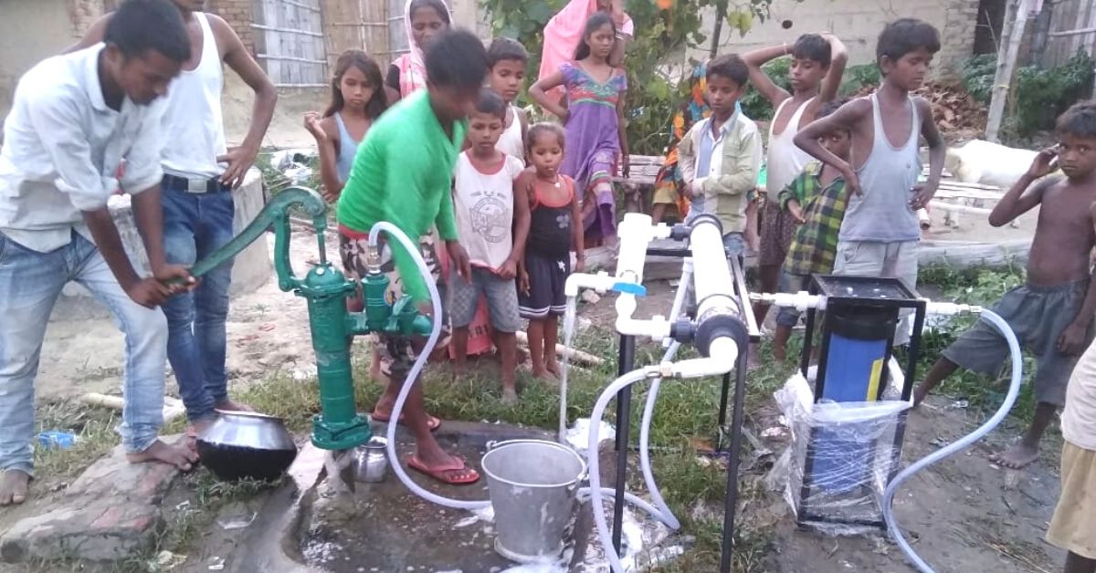 Villagers using Aquaplus purifier through hand pump to filter water.
