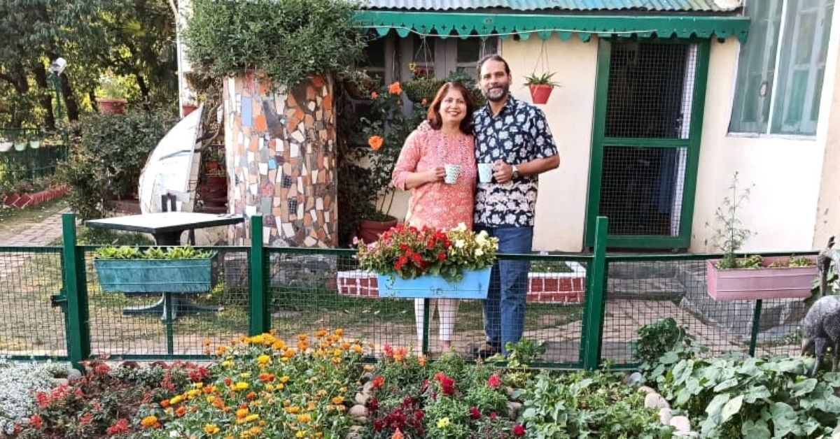 an indian couple standing outside their sustainable homestay in landour uttarakhand