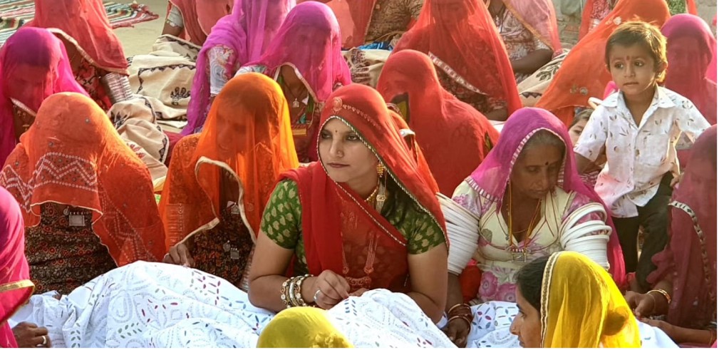 artisan ruma devi embroiders a bed sheet with other women artisans in barmer, rajasthan