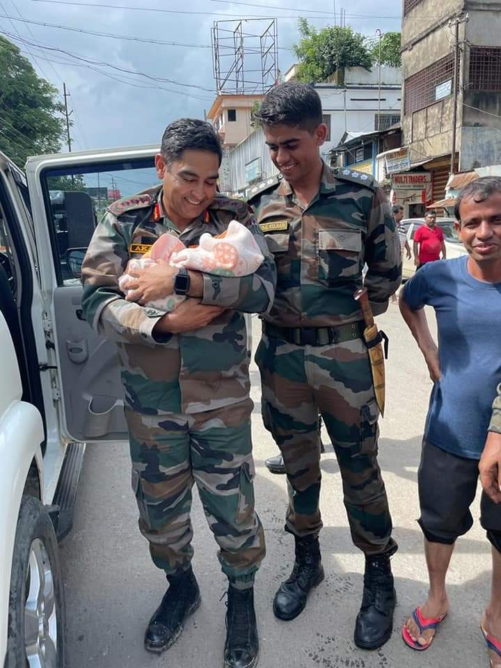 Assam Rifles officers hold and pose with the baby they rescued