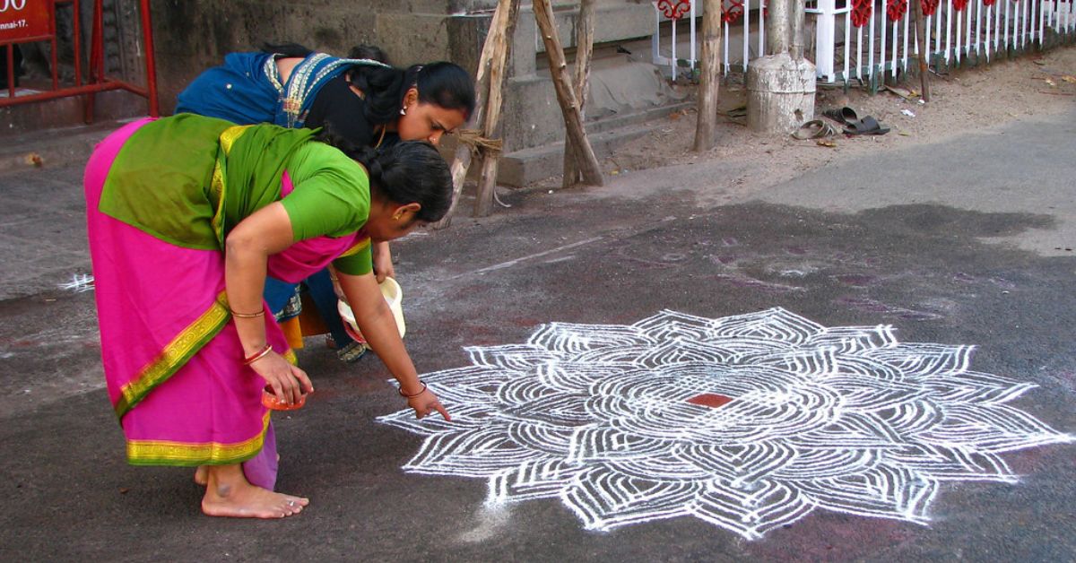 Women drawing kolam design outside their house