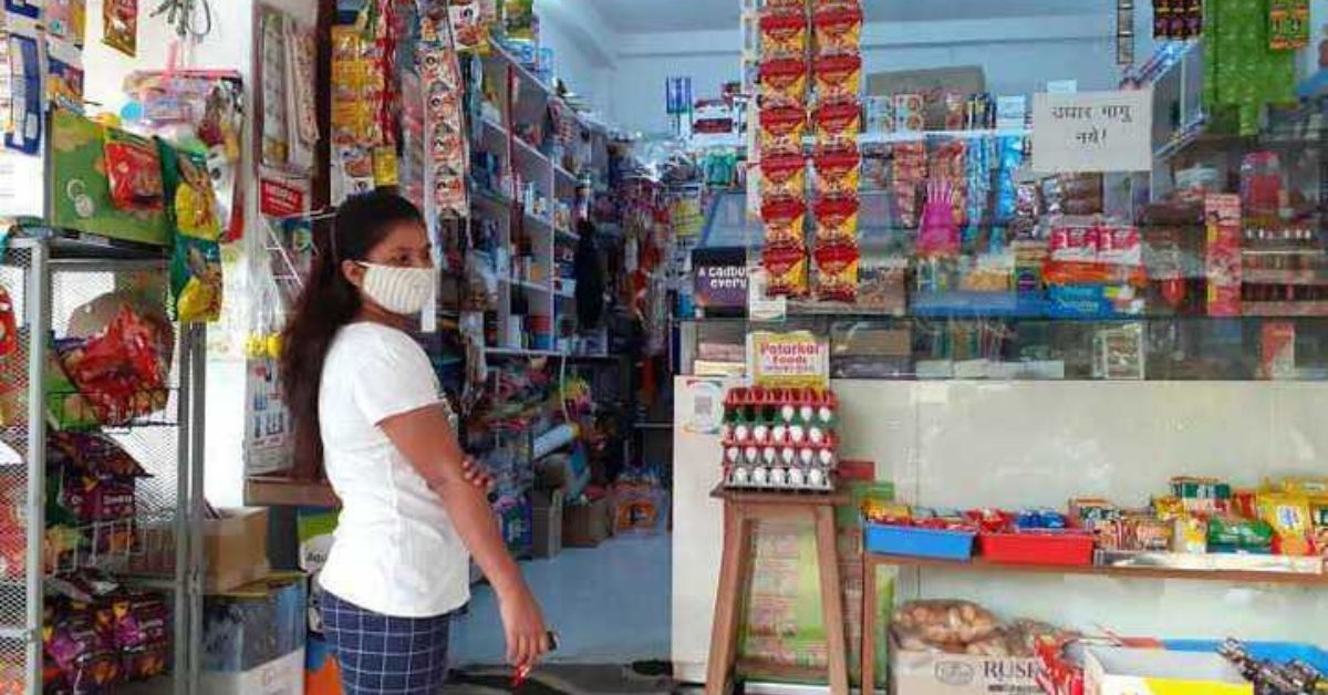 a masked woman stands outside a grocery store