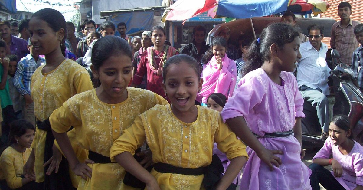 adolescent girls dressed in yellow perform at a nukkad naatak or street play in mumbai slums