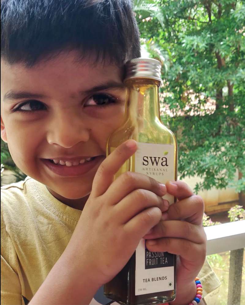 A little boy holding a syrup bottle. 