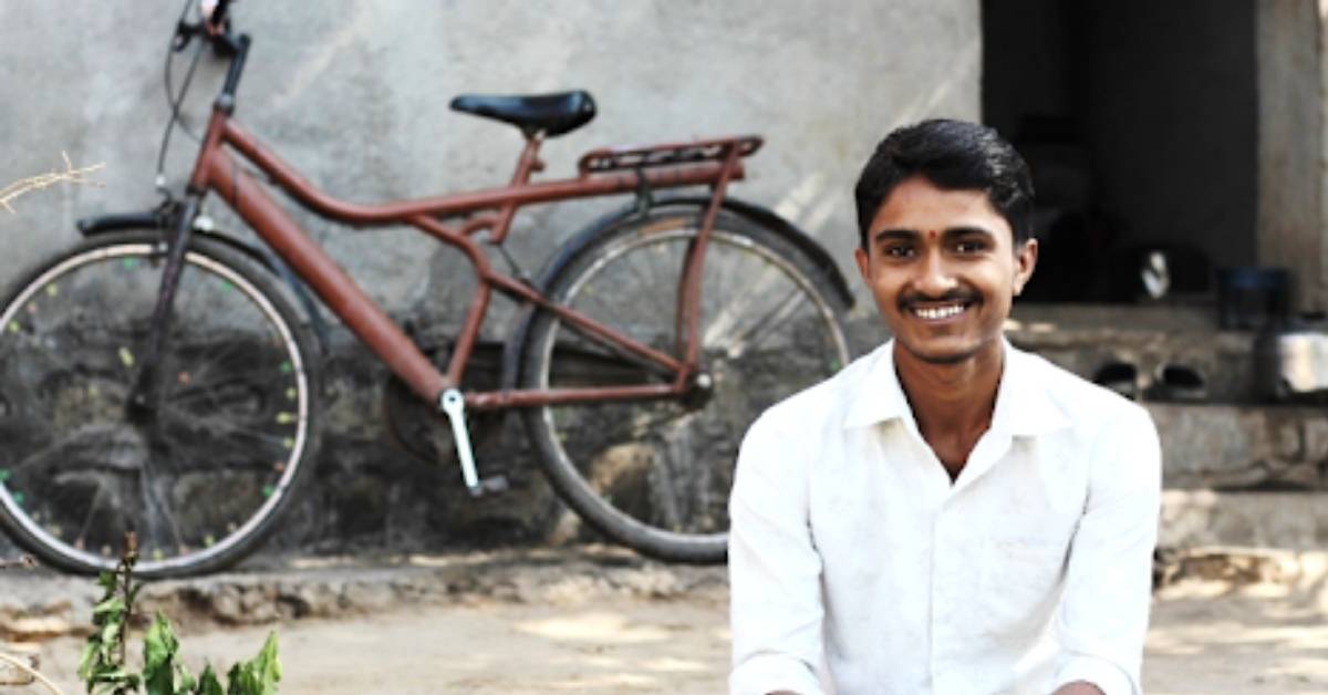 seorang pria bernama aatish tersenyum saat dia duduk di depan sebuah sepeda 