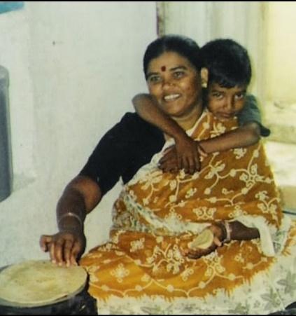 a young boy hugs his mother while she prepares food 