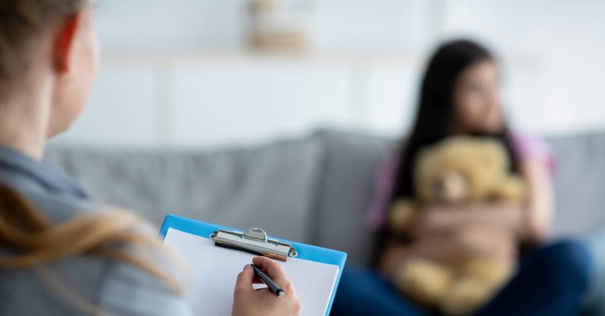 woman sitting on a couch takes therapy while counsellor takes notes