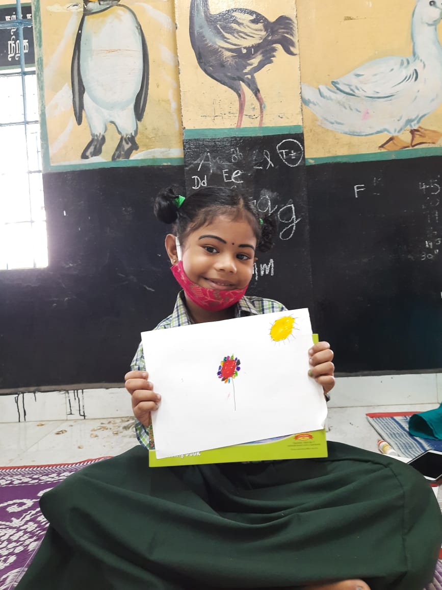 A student holding up a drawing that she has made during the art class. 