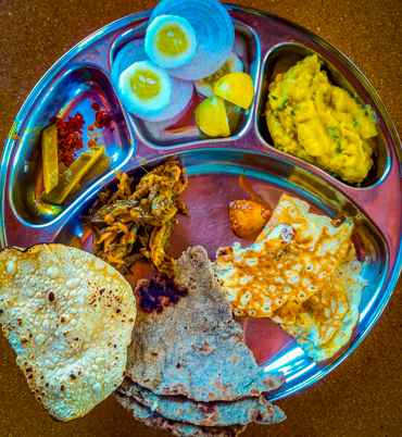 The food at Mohraan Farms is a delicious spread with roti, seasonal vegetables, pickles, and fruits