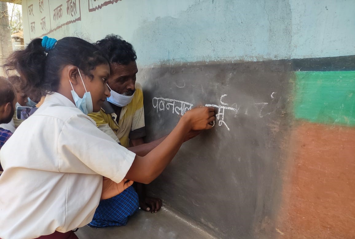 A child teaches parents in Dumka, Jharkhand.