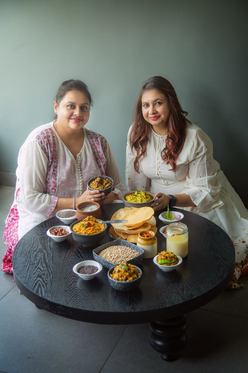 Ratika Bhargava dan Riccha Khetan, pendiri CauldronSisterss dengan meja khichdi dan makanan tradisional Jaipur