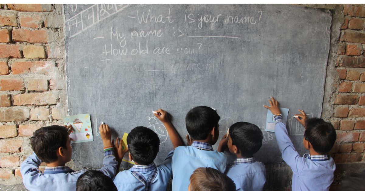 children in blue uniforms write and scribble on the board 