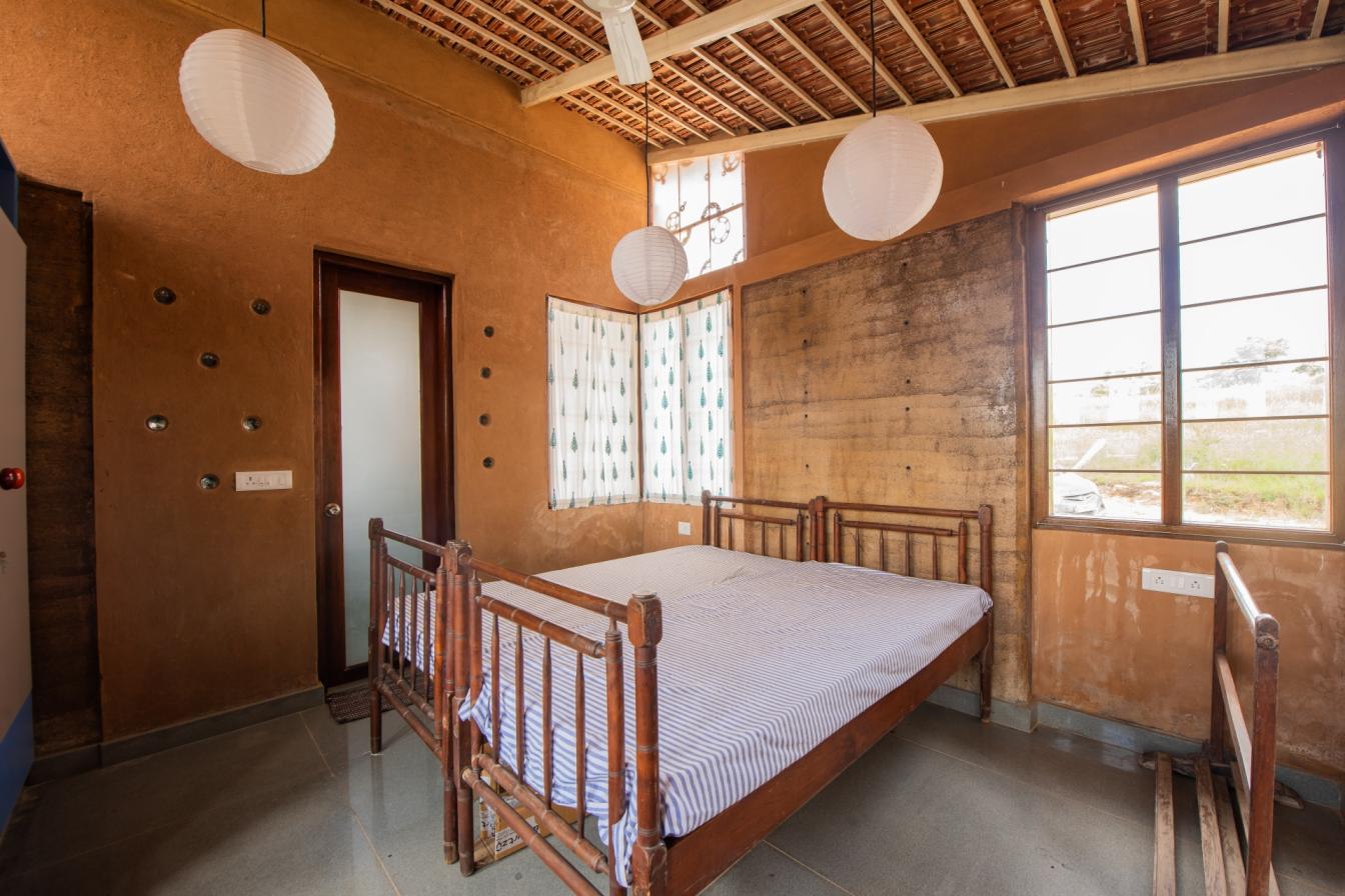 Kamar yang luas dan terang dengan atap genteng Mangalore, lantai batu, dan jendela kayu Honne.  