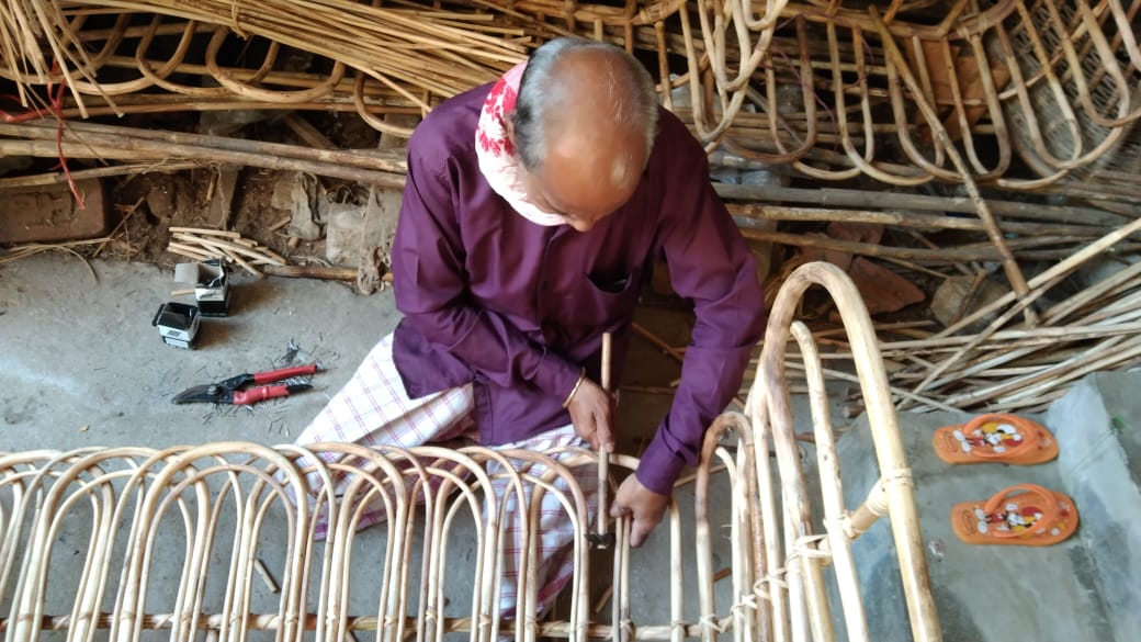 An artisan working on the cane weaving process to make a headboard