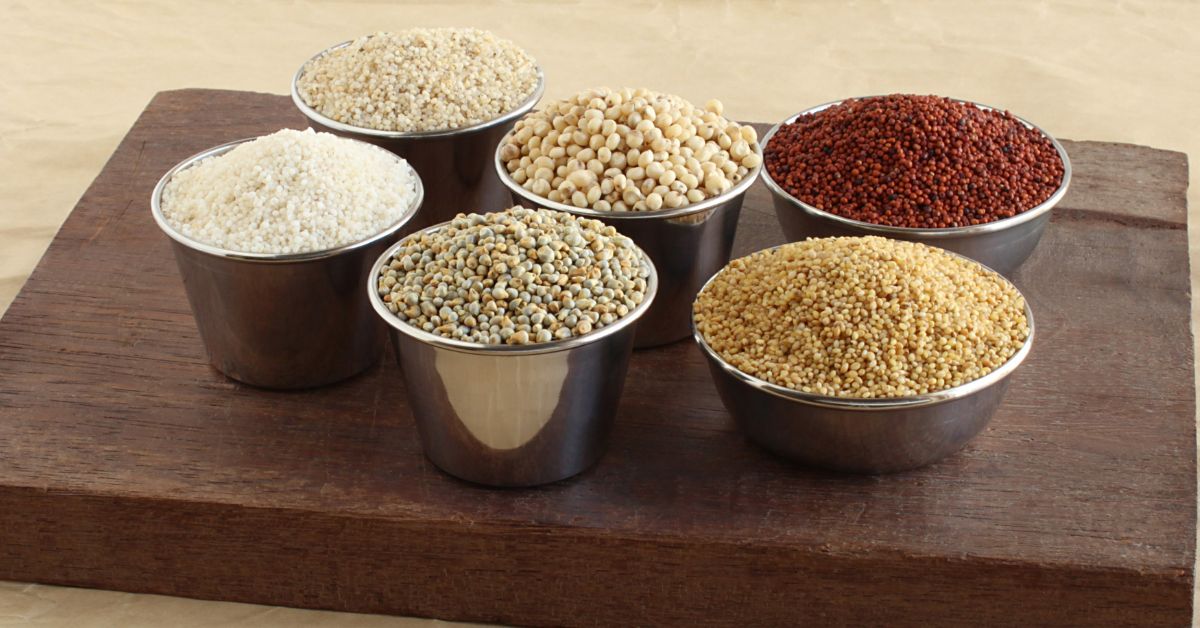 Millets, healthy vegetarian grains, including finger millet or ragi, foxtail millet, pearl millet or bajra, and kodo millet, in steel bowls.
