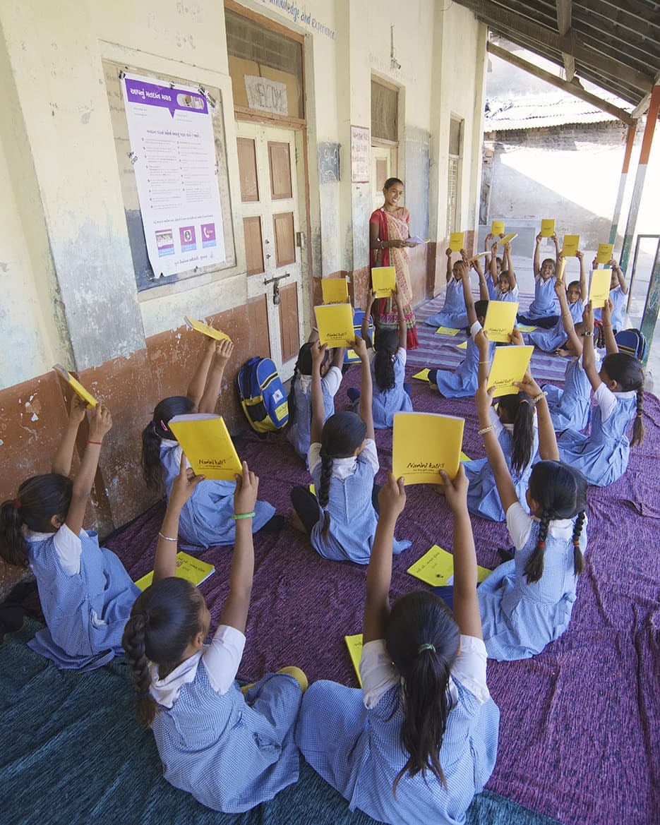School girls under the Nanhi Kali Project showing their notebooks to their teacher. 