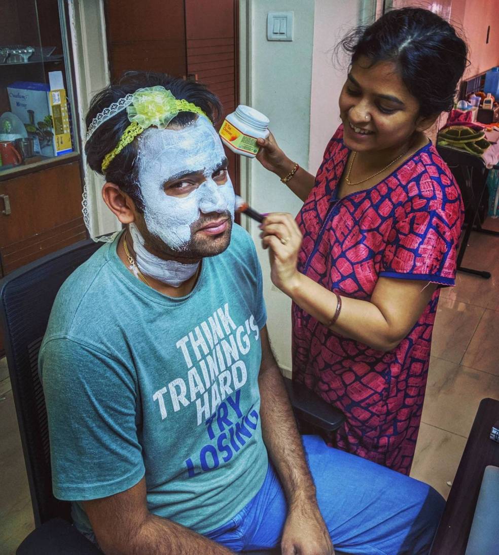 Sneha, helping her partner, Sourabh, put on a face mask. She put on their daughter’s hair bands on his head to prevent his hair from falling on his face.
