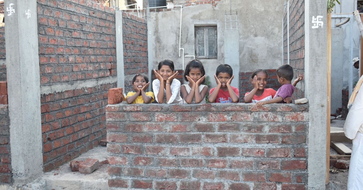Children from slum areas posing against the backdrop of their newly built homes