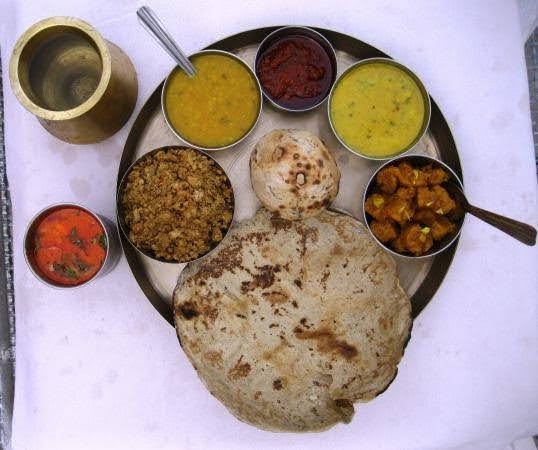 The food at the homestay includes Dal Bati Churma, which has masala bati, makki ki bati, and thirki dal
