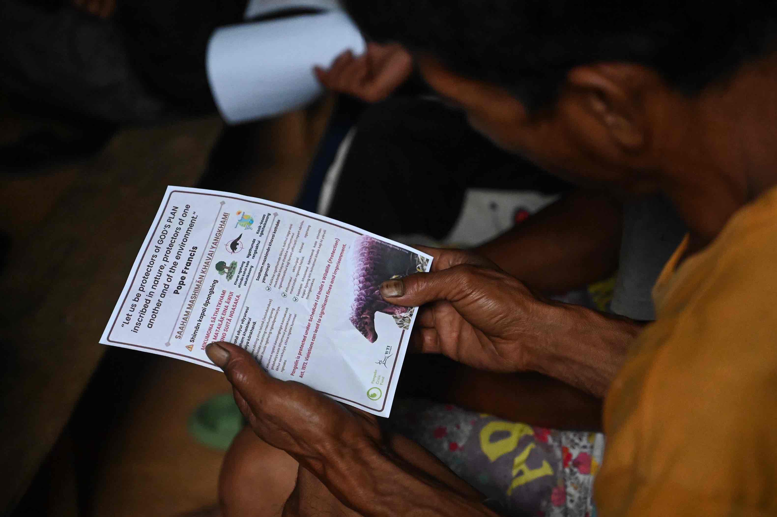 A man reads a brochure served at a community event on protecting pangolins in Ngainga Village, Manipur.